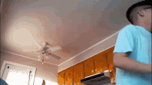 a man standing in a kitchen with a ceiling fan