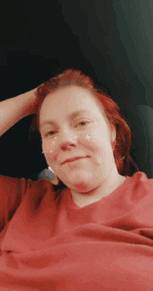 a woman with red hair is wearing a red sweater