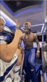 a man without a shirt is dancing on a bus with a man wearing a shirt that says dallas