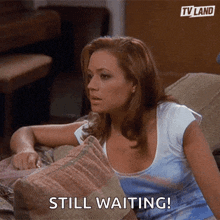 a woman is sitting on a couch with the words still waiting on her face