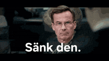 a man in a suit and tie stands in front of a sign that says " sankden "