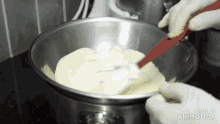 a person is mixing something in a metal bowl with a spatula and the words made in animatica visible