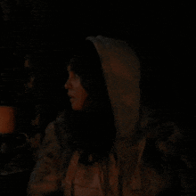 a person in a hooded jacket is holding a microphone in the dark