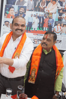 a man wearing an orange sash with a picture of a woman on it is standing next to another man