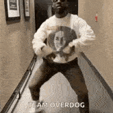 a man is dancing in a hallway wearing a shirt with a picture of a woman on it .