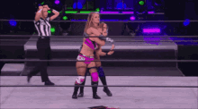 two women are wrestling in a ring with a referee watching .