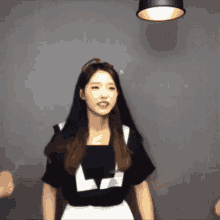 a woman with long hair is wearing a black shirt and white skirt .