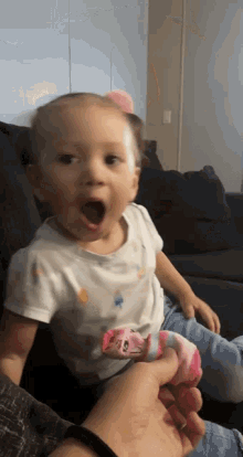 a little girl with a surprised look on her face is being held by a person