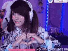 a girl making a heart shape with her hands while wearing headphones