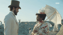 a man in a top hat stands next to a woman holding an umbrella with the hbo logo in the corner