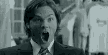 a man in a suit and tie is making a shocked face .