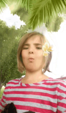 a young girl with a flower in her hair is wearing a striped shirt