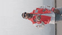 a man wearing a red and white varsity jacket with the letter g on it