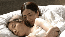 a couple of women laying on a bed with a clapper board behind them