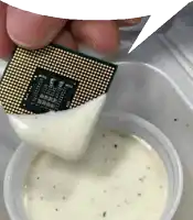 a chip that looks like a computer processor is being dipped in ranch dressing