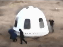 a group of people are standing around a white dome shaped object .