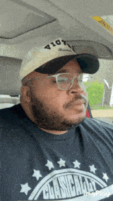a man wearing a hat and glasses is wearing a shirt that says " clasicsally "