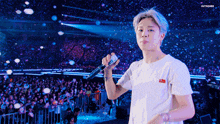 a man in a white shirt is holding a microphone in front of a crowd of people .