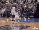 a basketball game is being played on a court with a crowd in the background .