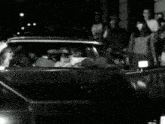 a man is sitting in a car talking on a phone .