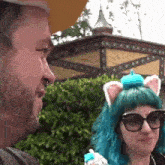 a man and a woman are standing next to each other and the woman has blue hair