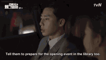 a man and a woman are sitting in a car and the woman says tell them to prepare for the opening event in the library too .