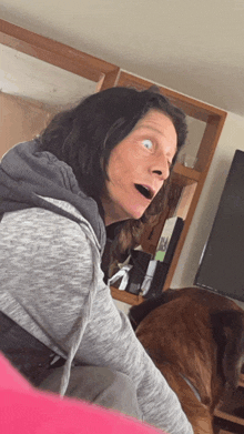 a woman with a surprised look on her face is sitting next to a brown dog