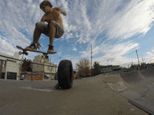 a skateboarder is doing a trick in a skate park with a tire in the foreground