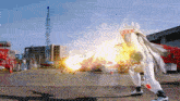 a person in a white costume is standing in front of a building with a fire coming out of it