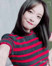 a woman in a red and black striped shirt is taking a selfie with the time of 00:00:12