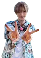 a young man wearing a floral shirt is giving the peace sign