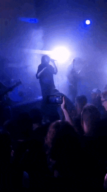 a man is singing into a microphone in front of a crowd of people