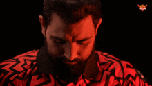 a man with a beard wearing a red and black shirt
