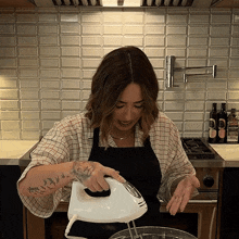 a woman with a tattoo on her arm uses a mixer