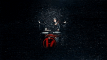 a man playing drums in a dark room with lights behind him