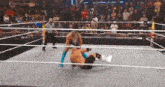 a wrestling match is taking place in a ring with a referee watching .