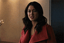 a woman in a red coat is standing in a hallway