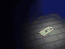 a green and gold motherboard is laying on a black brick floor