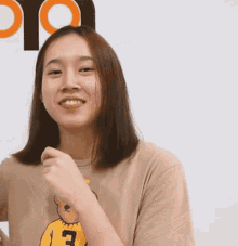 a woman wearing a tan shirt with a yellow teddy bear and the letter e on it