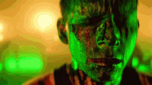 a man with green paint on his face is looking at the camera