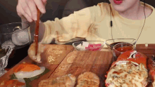 a person is eating a lot of food on a wooden cutting board .