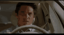 a man in a tie is driving a car