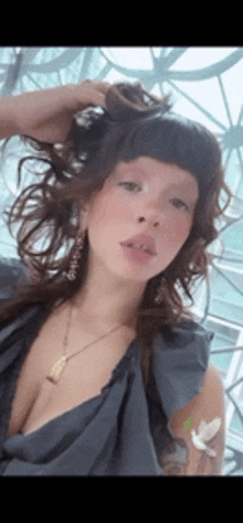 a woman with a tattoo on her arm is wearing a black dress and a necklace