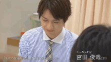 a man in a striped shirt and tie with kis-my-ft2 written above him