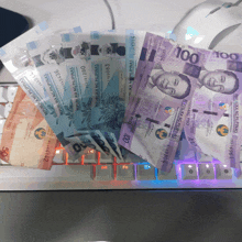 a bunch of money on top of a keyboard that says 100 on it