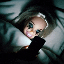 a barbie doll is laying in bed with a cell phone