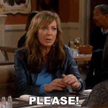 a woman sits at a table with the word please written on the table