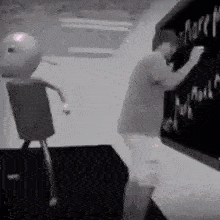 a man is writing on a blackboard while a robot is standing next to him .