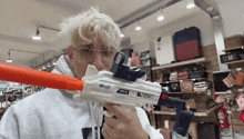 a man wearing glasses is holding a toy gun that says max on it
