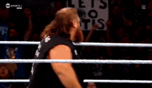 two men are wrestling in a wrestling ring with a referee .
